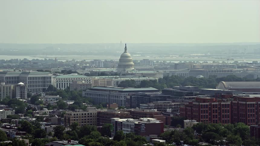 Stunning aerial footage of the iconic United States Capitol building in hazy Washington DC during the daytime perfect for tourism and sightseeing