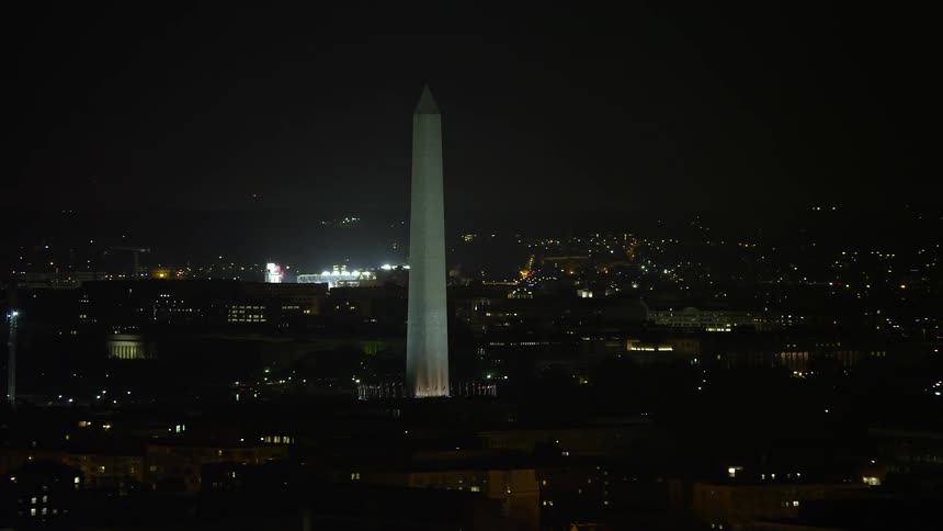 An aerial view of the iconic Washington Monument surrounded by American flags at night in Washington DC