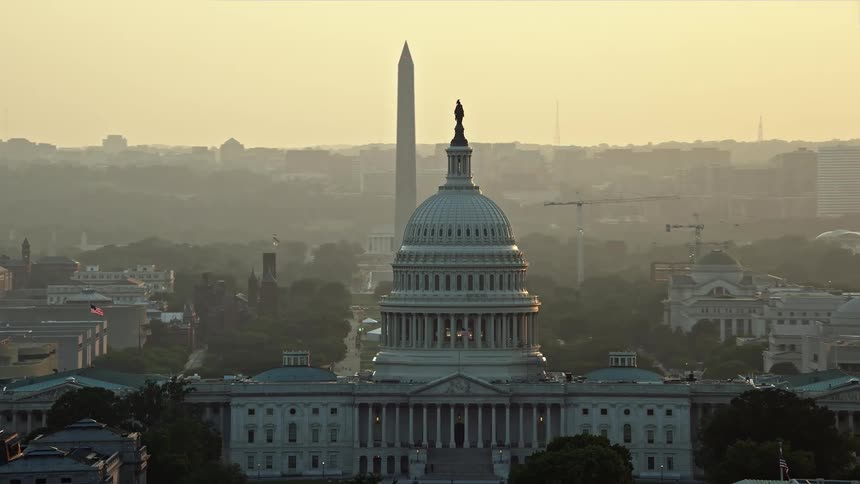 An iconic evening aerial view of the United States Capitol on Capitol Hill in the National Mall Washington DC revealing the famous Washington Monument during sunset