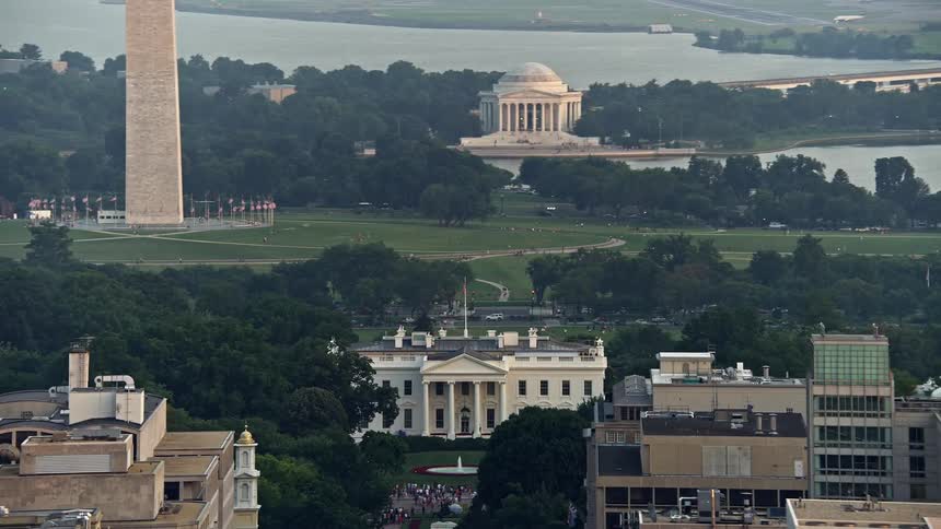 Aerial view of Jefferson Memorial and White House with a reveal of Washington Monument base during sunset in Washington DC