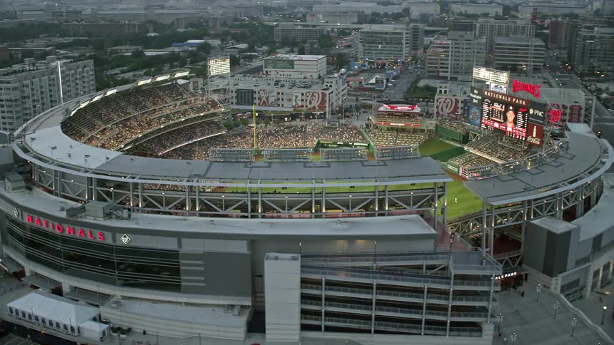 Aerial footage of Nationals Park during a baseball game packed with fans and set against a twilight sky in Washington DC
