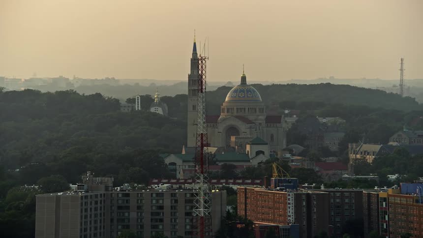 A stunning aerial view of the Basilica of the National Shrine of the Immaculate Conception in Washington DC during dusk with a beautiful sunset in the background