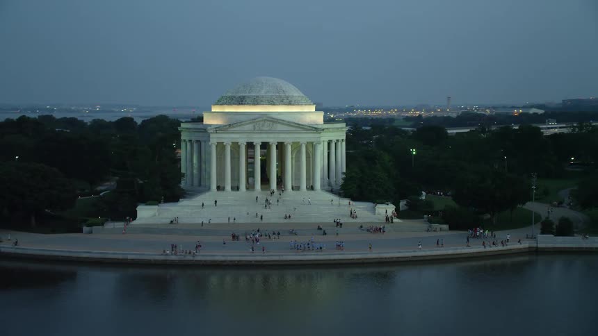Aerial footage approaching and flying by the lit-up Jefferson Memorial during twilight in Washington DC