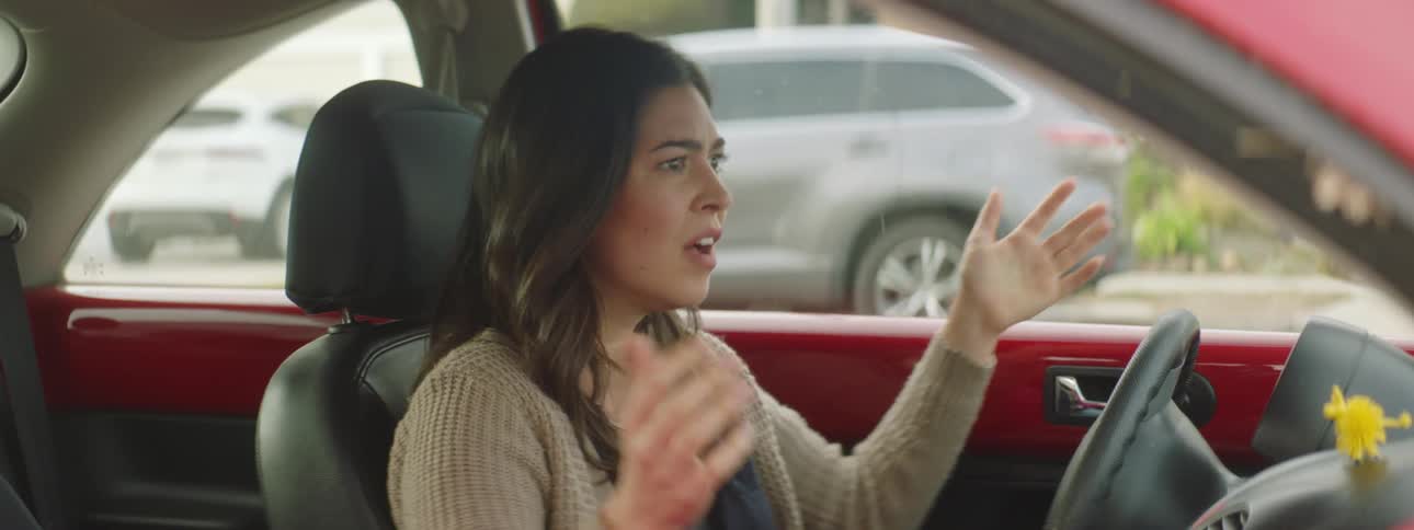 A woman upset in her car throwing her hands up and then driving away