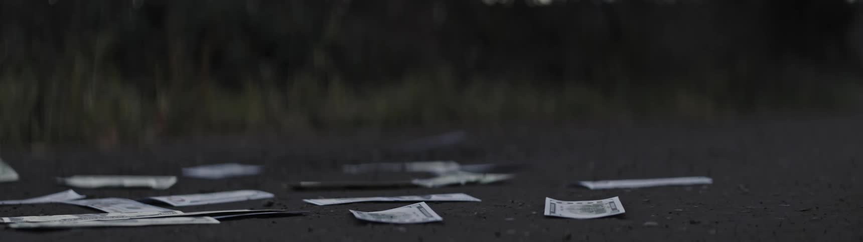 Dollar bills being pushed around on the ground by the wind