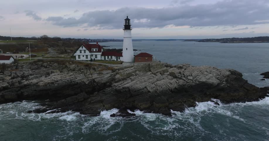 A white lighthouse sits above a stormy ocean