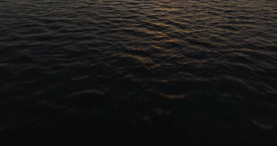 Camera soars over ocean and tilts down to see the waves below