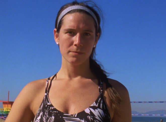 A woman staring at the camera with a braid in her hair wearing a bathing suit