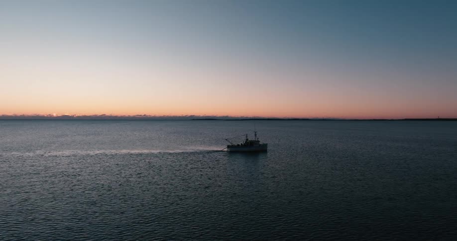 A lone fishing boat working at sunrise