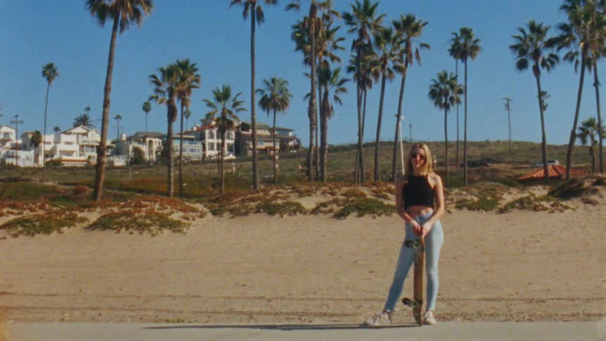 A woman standing holding a skateboard twisting it around