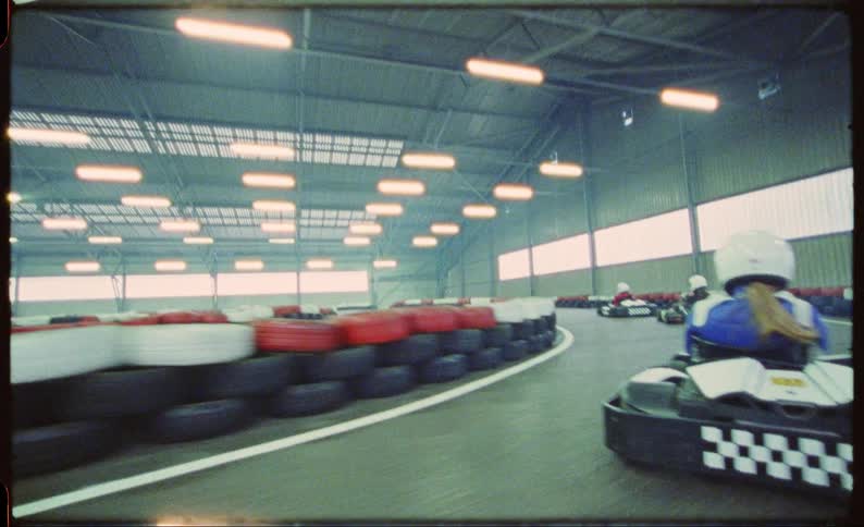 People riding race cars on an indoor track