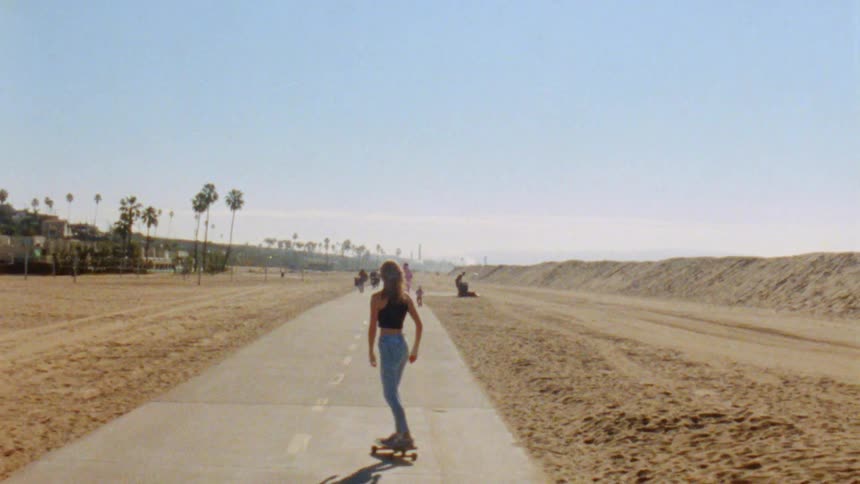Woman skating down the road with people in the distance