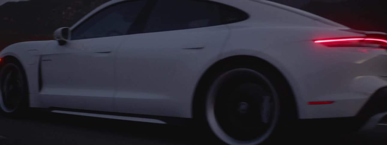 A white sports car driving down the road in a mountain area