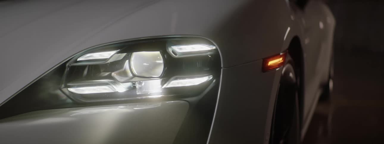 The headlights of a parked gray sports car turn on