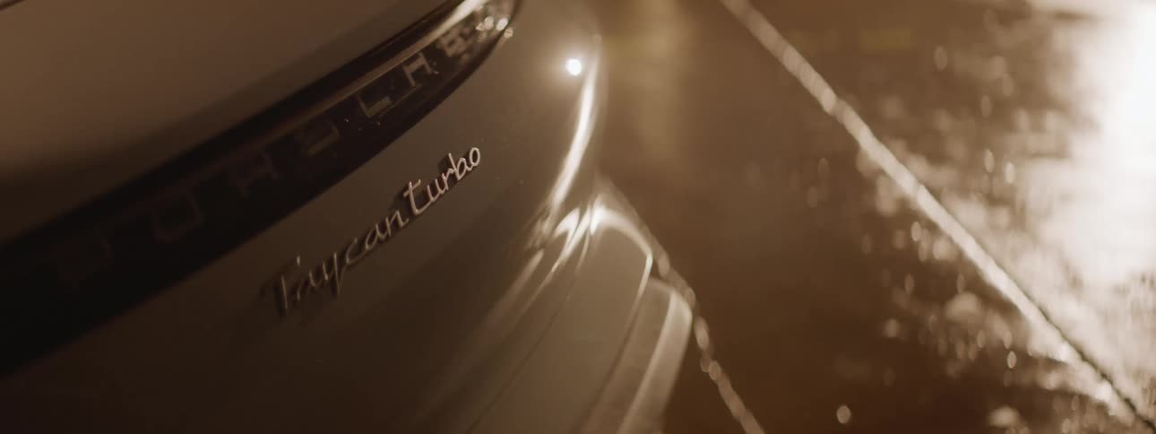 A close up of a back end of a white car as a person walks by