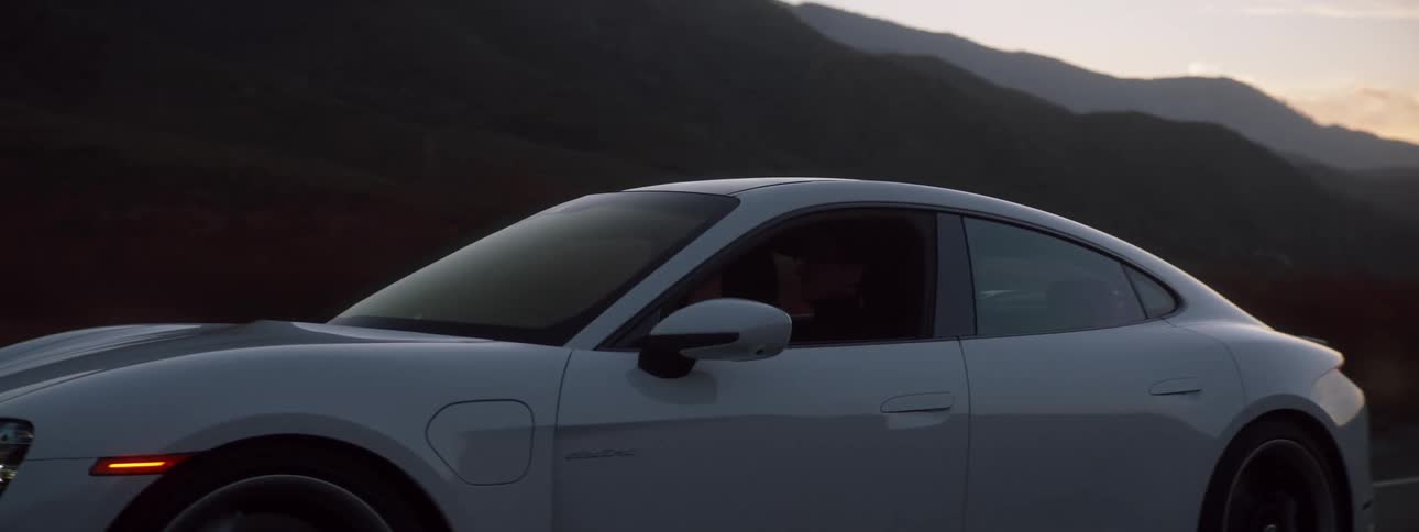 Car moving down the road at high speeds the camera pans to the drivers face for a split moment before the camera is pulled away