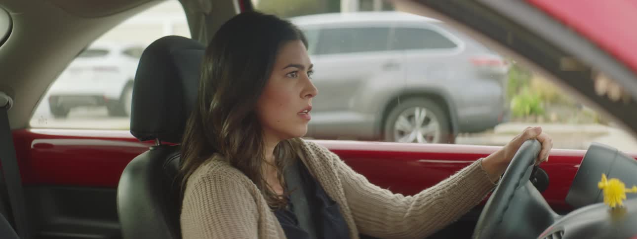 Confused young woman sitting on the drivers seat of a parked car waits impatiently