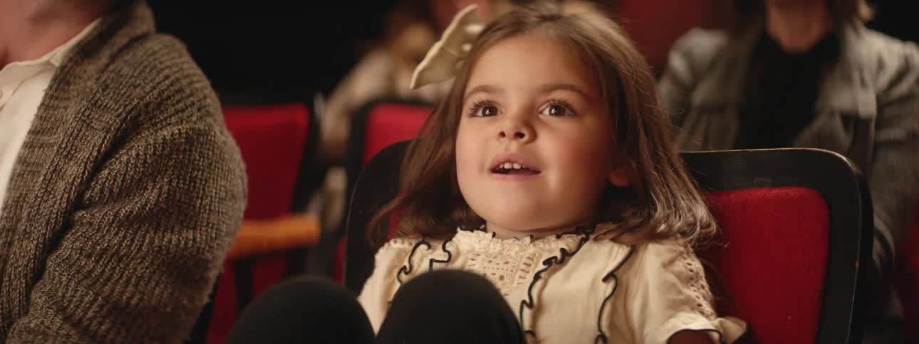 Girl sitting in audience looks awed and surprised before clapping with the others