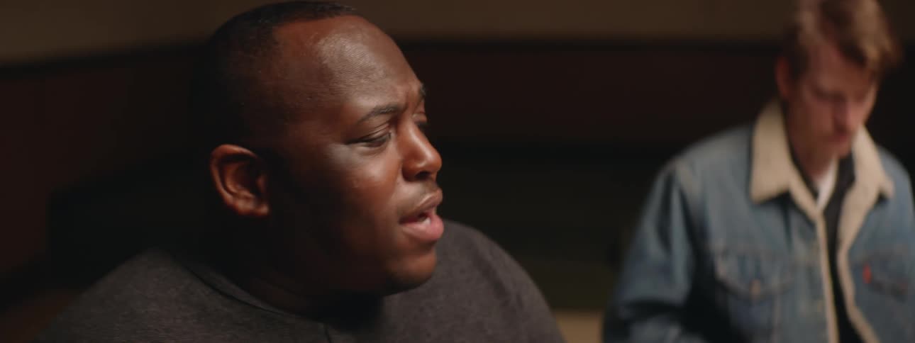 Close up of the face of a man sitting on a room talking to friends