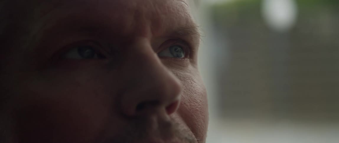 A person is outside standing still blinking their eyes