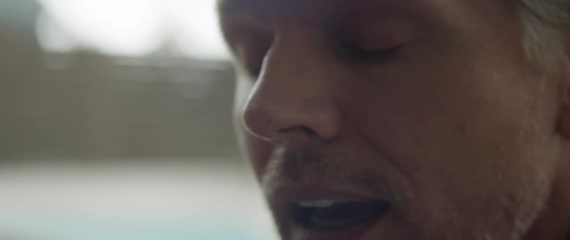 A man with facial hair singing with his eyes closed
