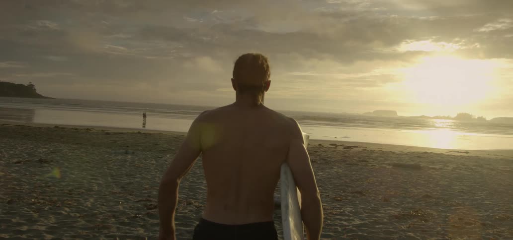 A man is walking towards the ocean with a surfboard
