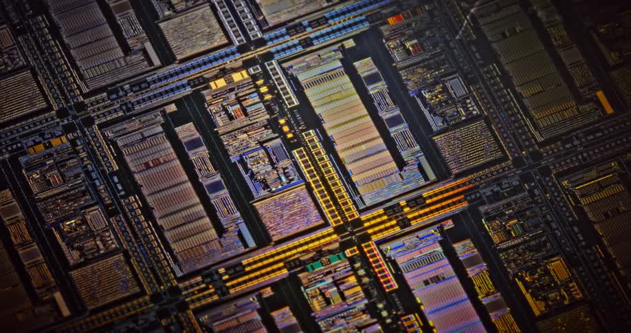 Light shines upon electronic components as they lay across a dark surface in rows