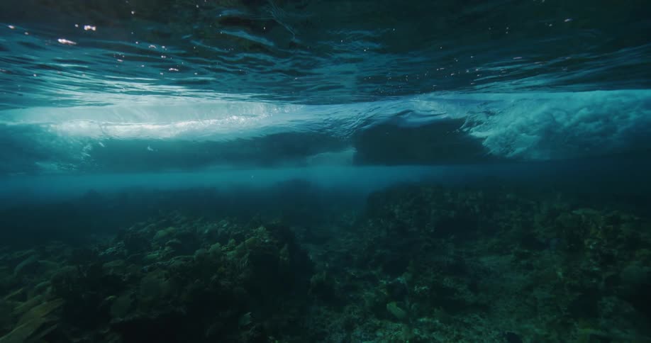 Wave rolls across surface shadowing seafloor