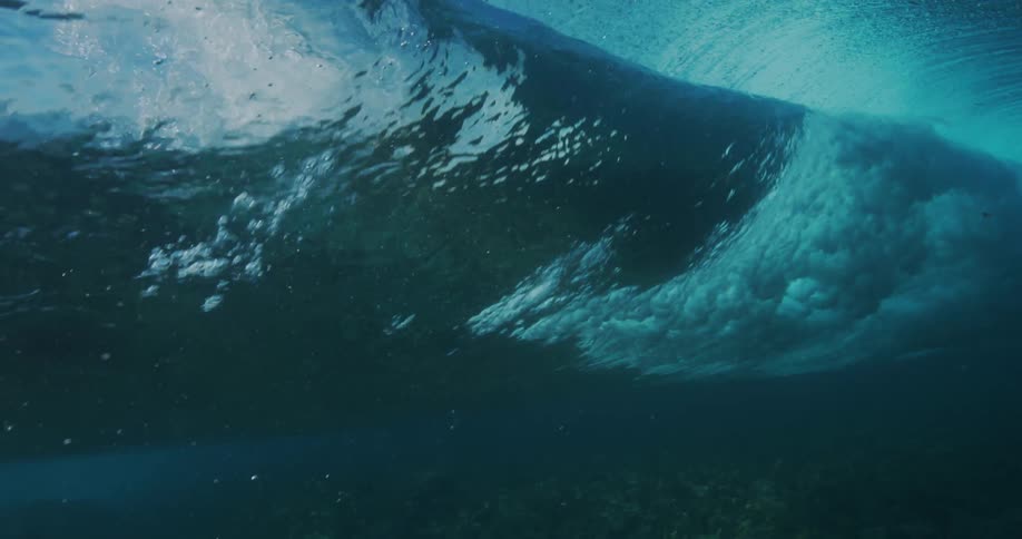 Sunlight reflects on the water as a wave rolls over the seabed