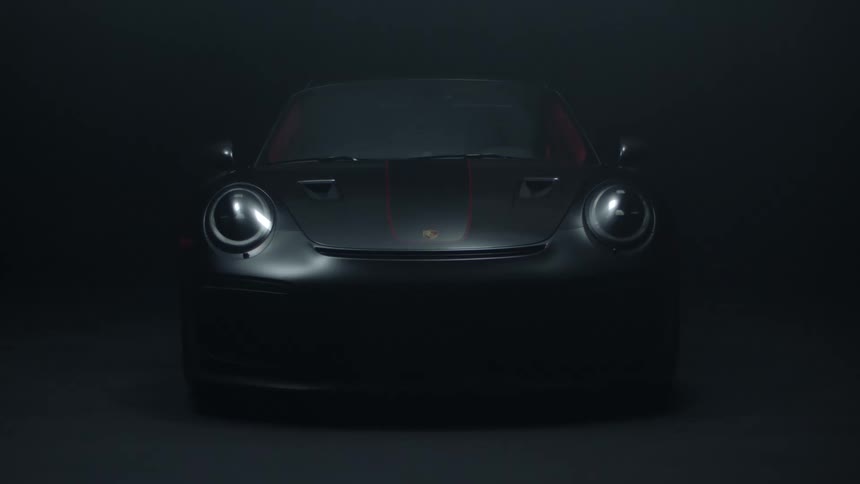 Light shines on a gray sports car parked in the darkness