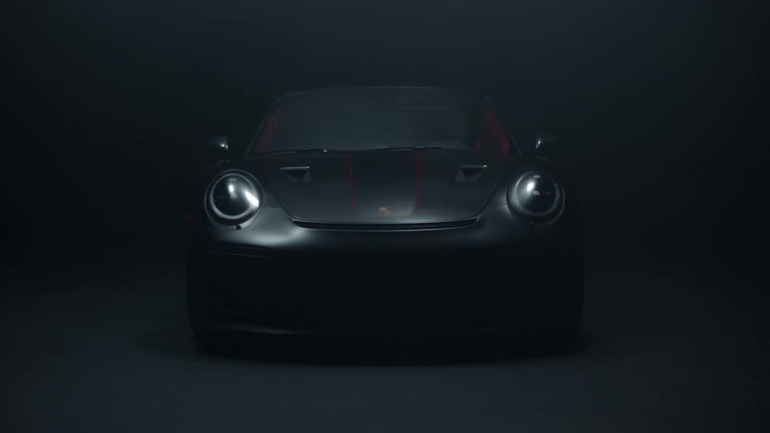 Light shines on a gray car parked in the darkness