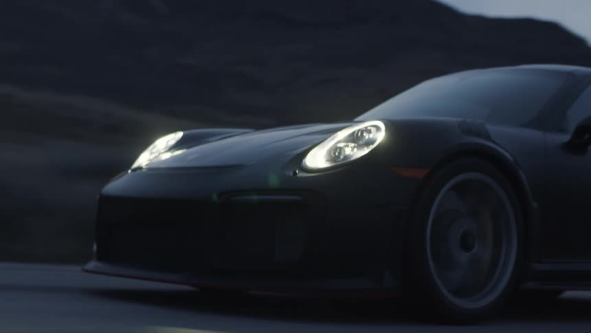 A black sports car driving down the road in the dusk with its headlights on