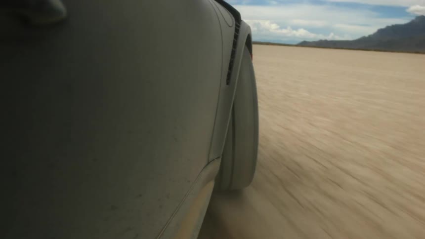 A car is driving off road in a desert area