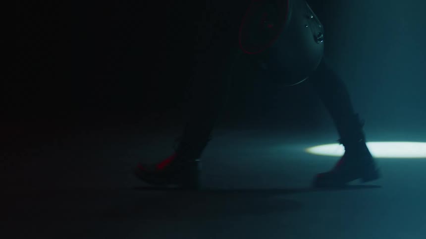 A person walks through a parking garage carrying a crash helmet