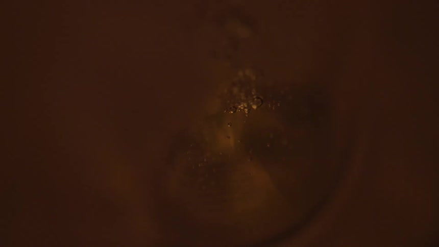 Small bubbles rise from a gold substance as a light flashes