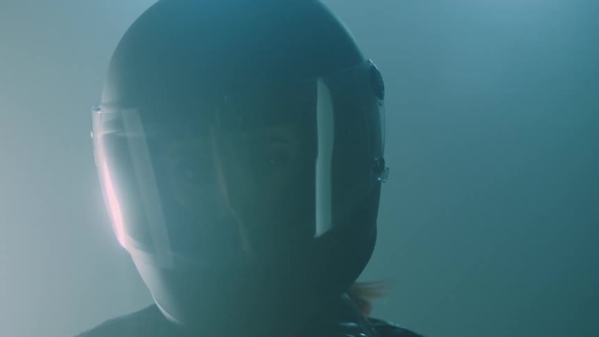 A woman wearing a helmet turns her head to face forward