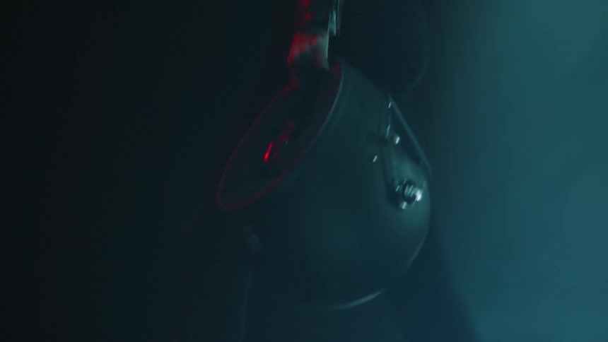 A person wearing black walks holding a black helmet