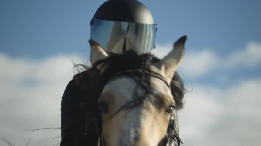 A person wearing a black jacket and helmet riding a horse