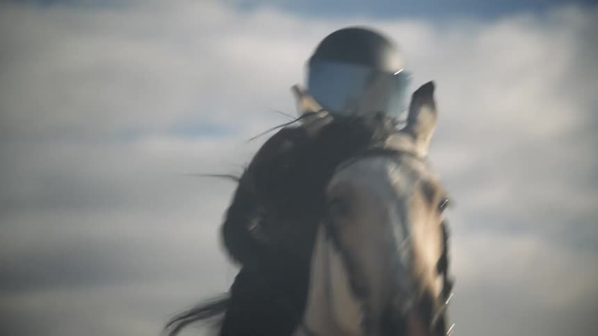 A tan horse with a rider in all black riding through the desert