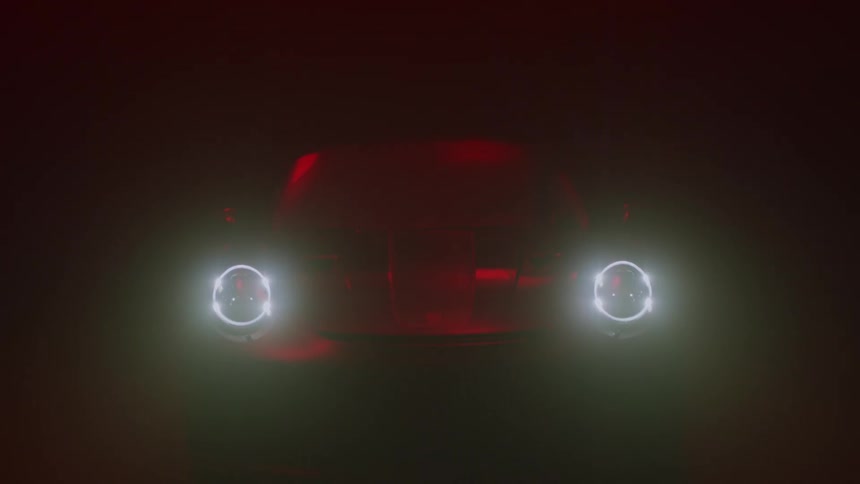 A car with headlights on sitting in the dark