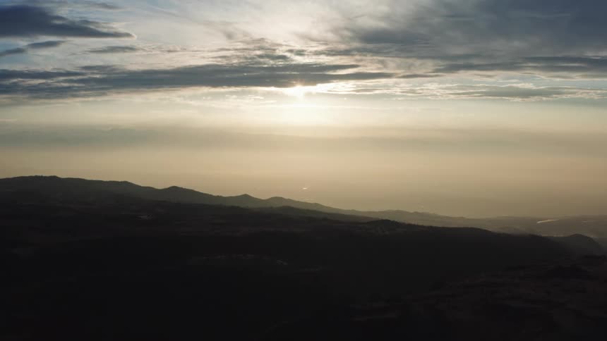 A silhouette landscape of mountains against a sunlit sky