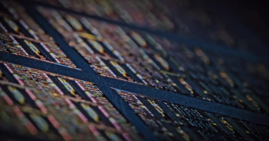 Light shines upon electronic components as they lay across a dark surface in rows and squares