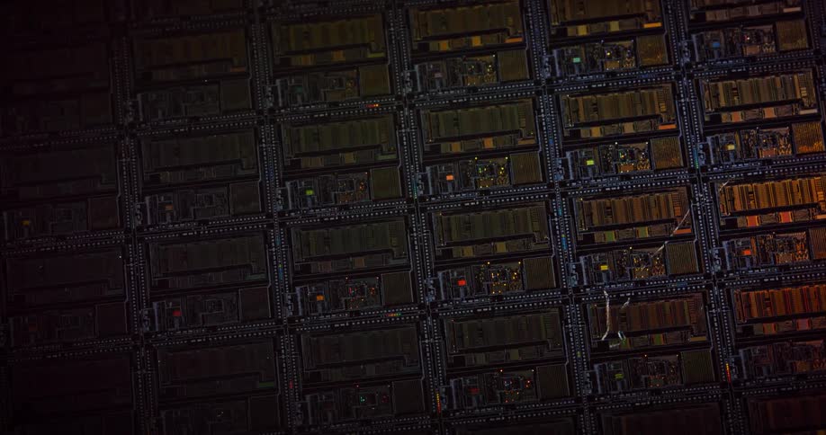 Light shines upon electronic components as they lay across a dark surface in rows