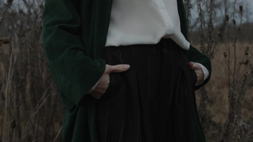 A person is standing in a field with their hands in their pockets