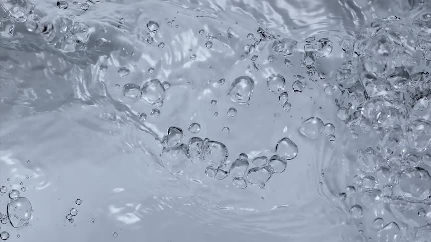 Clear liquid water is being poured and splashes