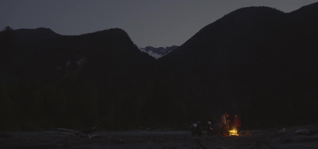 People gathered around a campfire in the mountains
