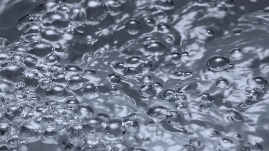 Bubbles are rising to the surface of water and shining in the light