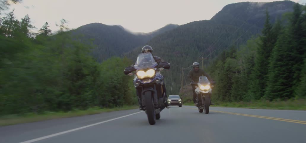 Motorcyclists riding on a paved road with a single car following them