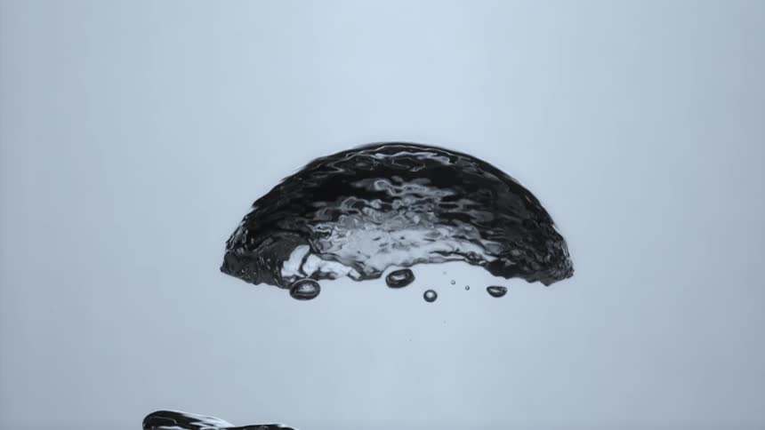 A large air bubble rises in a glass of water