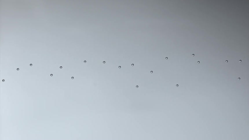 Stream of air bubbles slowly floating from left to right over a gray background